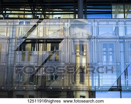 Stock Photograph - Facade of a building viewed through panels of glass with reflections of yellow and blue; Belgrade, Vojvodina, Serbia. Fotosearch
