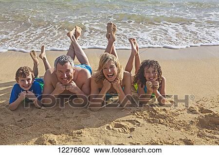 Stock Image - Family of four on a beach; Kailua, Island of Hawaii, Hawaii, United States of America. Fotosearch