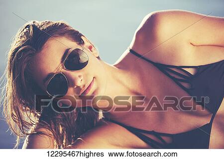 Stock Photograph - Fashion Lifestyle, Beautiful Woman In Swimwear Relaxing By The Pool At Sunset. Fotosearch