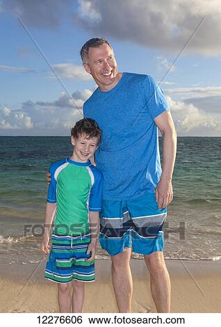 Father and son standing on a beach; Kailua, Island of Hawaii, Hawaii, United States of America View Large Photo Image Stock Photograph - Father and son standing on a beach; Kailua, Island of Hawaii, Hawaii, United States of America. Fotosearch