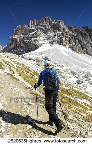 Female hiker on steep trail with rugged mountain peaks and blue sky in the background; Sesto, Bolzano, Italy View Large Photo Image Stock Photograph - Female hiker on steep trail with rugged mountain peaks and blue sky in the background; Sesto, Bolzano, Italy. Fotosearch