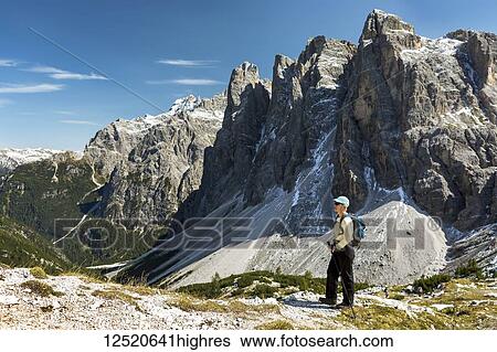 Female hiker overlooking valley against rugged mountain range and blue sky; Sesto, Bolzano, Italy View Large Photo Image Stock Photograph - Female hiker overlooking valley against rugged mountain range and blue sky; Sesto, Bolzano, Italy. Fotosearch