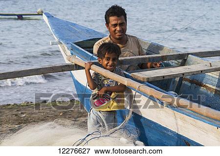 Fisherman in his boat and boy; Dili, East Timor View Large Photo Image Stock Photo - Fisherman in his boat and boy; Dili, East Timor. Fotosearch