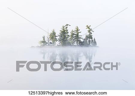 Stock Photograph - Fog shrouds a small island on Turtle Lake in Ontario's Muskoka Region, near Rosseau; Ontario, Canada. Fotosearch