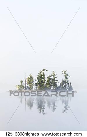 Stock Photograph - Fog shrouds a small island on Turtle Lake in Ontario's Muskoka Region, near Rosseau; Ontario, Canada. Fotosearch