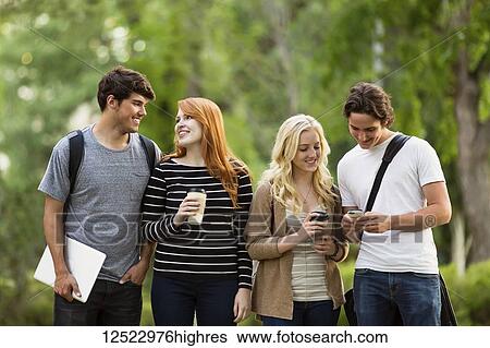 Stock Photograph - Four friends walking and talking on the university campus; Edmonton, Alberta, Canada. Fotosearch