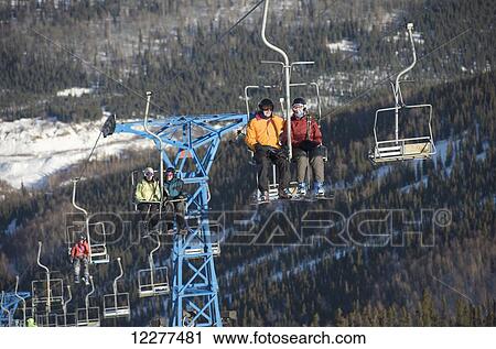 Stock Image - Friends ride the 3800-feet double chairlift at Mt. Aurora Skiland near Cleary Summit north of Fairbanks, Alaska.. Fotosearch