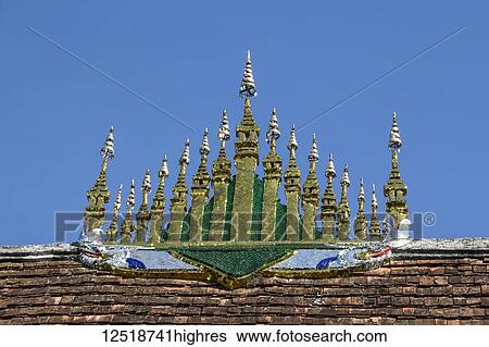 Stock Photograph - Gilded ornamental element consisting of 17 miniature stupas covered by 7 tiered parasols atop the roof of the sim (congregation hall) of Wat Xieng Thong; Luang Prabang, Laos. Fotosearch
