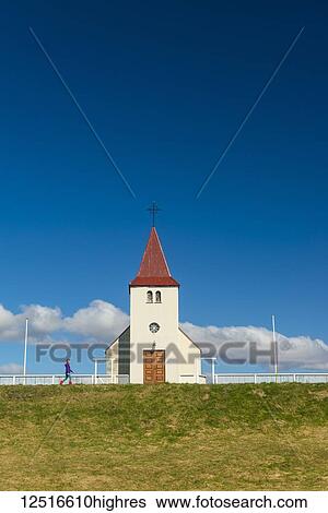 Stock Photograph - Girl walking past small church; Langaholt, Iceland. Fotosearch
