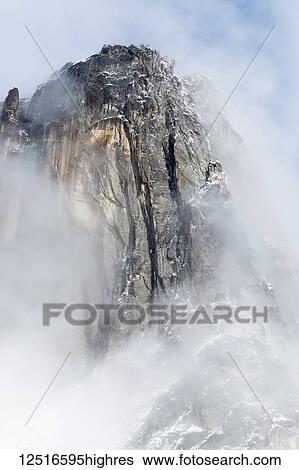 Stock Photograph - Granite spire surrounded by clouds, Yosemite National Park, California, United States of America. Fotosearch