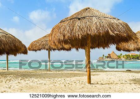 Stock Photograph - Grass beach umbrellas next to the Caribbean ocean; Playa Del Carmen, Quintana Roo, Mexico. Fotosearch