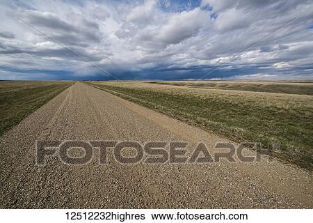 Stock Photograph - Gravel road heading into the stormy distance, rural Saskatchewan; Saskatchewan, Canada. Fotosearch