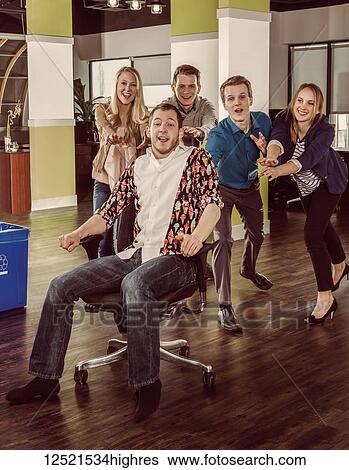 Group of young millennials pushing a co-worker across the room in his chair; Sherwood Park, Alberta, Canada View Large Photo Image Stock Photograph - Group of young millennials pushing a co-worker across the room in his chair; Sherwood Park, Alberta, Canada. Fotosearch