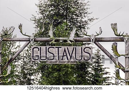 Stock Photograph - Gustavus sign on front lawn of house near ferry dock in Gustavus, Alaska; also says 'Alaskans Like Big Racks' with many moose racks nailed to sign; Alaska, United States of America. Fotosearch