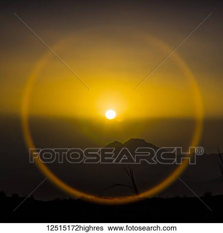 Halo around the glowing, golden sun over the silhouetted sand dunes of the Namib Desert; Sossusvlei, Hardap Region, Namibia View Large Photo Image Stock Photograph - Halo around the glowing, golden sun over the silhouetted sand dunes of the Namib Desert; Sossusvlei, Hardap Region, Namibia. Fotosearch