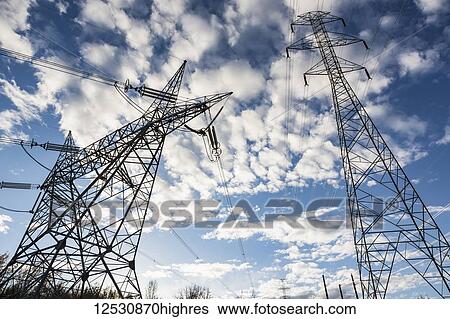 Stock Photograph - High voltage power transmission towers against a blue sky with cloud at dusk; Edmonton, Alberta, Canada. Fotosearch