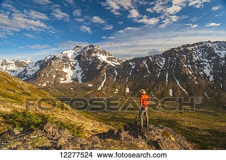Hiker on rock outcrop overlooks Powerline Pass valley and trail, Chugach State Park, Southcentral Alaska View Large Photo Image Picture - Hiker on rock outcrop overlooks Powerline Pass valley and trail, Chugach State Park, Southcentral Alaska. Fotosearch