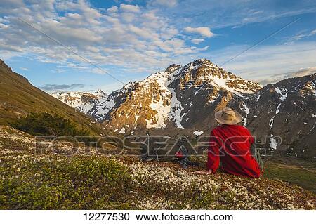 Hiker rests on a hillside overlooking Powerline Pass valley and trail, Chugach State Park, Southcentral Alaska View Large Photo Image Stock Image - Hiker rests on a hillside overlooking Powerline Pass valley and trail, Chugach State Park, Southcentral Alaska. Fotosearch