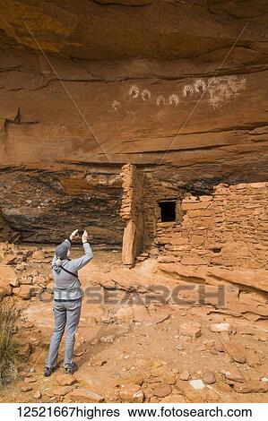 Stock Photograph - Hiker taking a photograph, Ancestral Pueblo, up to 1, 000 years old, Bears Ears National Monument; Utah, United States of America. Fotosearch