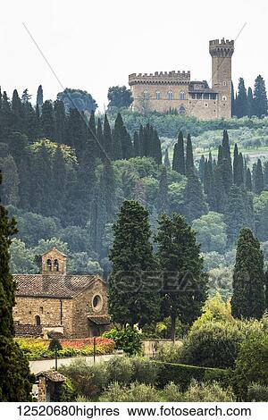 Stock Photograph - Hillside covered with trees in the mist and a stone church in the valley and castle on hilltop; Italy. Fotosearch