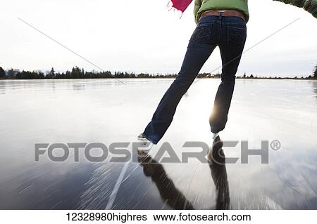 Stock Photograph - Ice skating on a frozen lake; Alaska, United States of America. Fotosearch