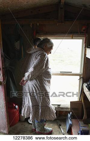 Stock Photograph - Inuit elder looking out the window of her cabin; Cambridge Bay, Victoria Island, Nunavut, Canada. Fotosearch