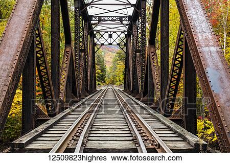 Stock Photograph - Iron railroad bridge over Sawyer River with trees in autumn colours, White Mountains National Forest; New England, United States of America. Fotosearch