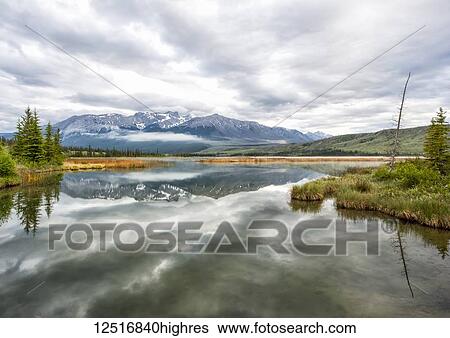 Stock Photograph - Lake reflections and the Rocky Mountains near Jasper in the early morning, Jasper National Park; Alberta, Canada. Fotosearch