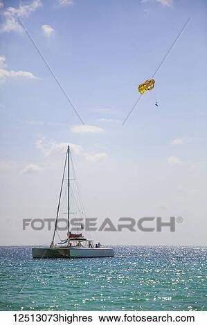 Stock Photograph - Large catamaran and parasailer on open tropical water; Negril, Jamaica. Fotosearch