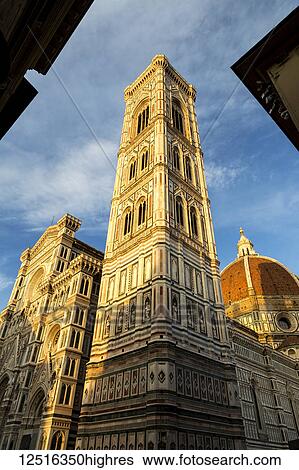 Stock Photograph - Large decorative cathedral with tower and dome with blue sky and clouds glowing orange at sunset. Fotosearch