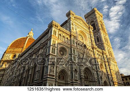 Stock Photograph - Large decorative cathedral with tower and dome with blue sky and clouds glowing orange at sunset. Fotosearch