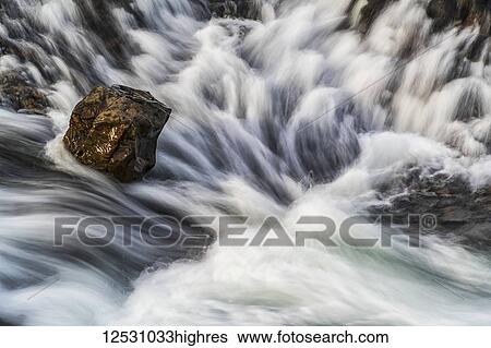 Stock Photograph - Long exposure of water flowing over rocks; Djupavik, West Fjords, Iceland. Fotosearch