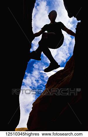 Looking upwards to the silhouette of a climber in a slot canyon in the desert; Hanksville, Utah, United States of America View Large Photo Image Stock Photograph - Looking upwards to the silhouette of a climber in a slot canyon in the desert; Hanksville, Utah, United States of America. Fotosearch