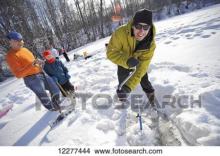Picture - Man augers an ice fishing hole on Matanuska Lake while on a ice fishing trip in the Matanuska Valley north of Anchorage, Southcentral Alaska, winter. Fotosearch