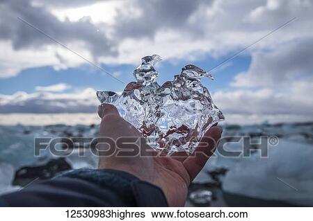 Stock Photograph - Man holding a piece of ice at Jokulsarlon, South coast; Iceland. Fotosearch