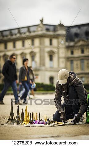 Man prepares to sell eiffel tower miniatures to tourists outside the Louvre; Paris, France View Large Photo Image Stock Photo - Man prepares to sell eiffel tower miniatures to tourists outside the Louvre; Paris, France. Fotosearch