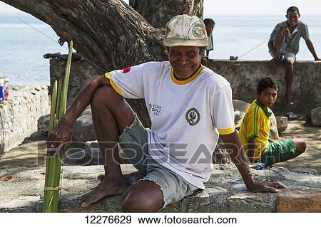 Man sitting on a stone ledge at the beach; Manatuto, East Timor View Large Photo Image Stock Photo - Man sitting on a stone ledge at the beach; Manatuto, East Timor. Fotosearch