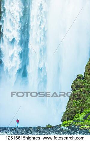 Man standing at base of Skogafoss waterfall; Iceland View Large Photo Image Stock Photograph - Man standing at base of Skogafoss waterfall; Iceland. Fotosearch