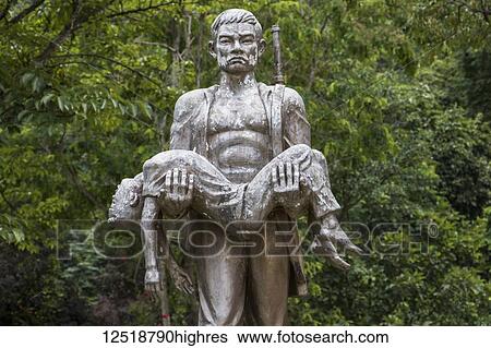 Stock Photograph - Memorial statue by Tham Piu Cave, place where on 24 November 1969, a single rocket fired from a US aircraft killed an estimated 374 people who had taken refuge in the cave; Xiangkhouang, Laos. Fotosearch