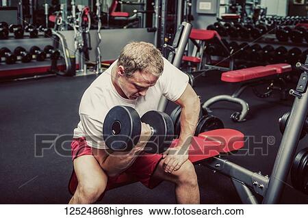 Stock Photograph - Middle-aged man working out and doing bicep curls at a fitness facility; Spruce Grove, Alberta, Canada. Fotosearch