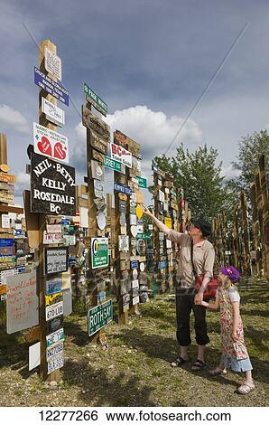 Stock Photograph - Mother and daughter explore the Signpost Forest, Watson Lake, Yukon Territory, Canada, summer. Fotosearch