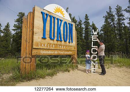 Mother and daughter stand next to a Welcome and Yukon sign, Yukon Territory, Canada, summer View Large Photo Image Picture - Mother and daughter stand next to a Welcome and Yukon sign, Yukon Territory, Canada, summer. Fotosearch