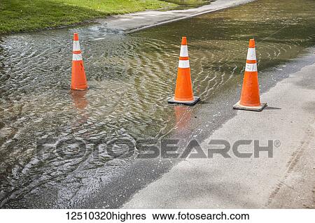 Orange traffic cones lined up warning of a partially flooded street; Connecticut, United States of America View Large Photo Image Stock Photograph - Orange traffic cones lined up warning of a partially flooded street; Connecticut, United States of America. Fotosearch