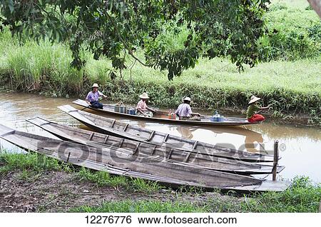 Stock Photograph - People riding in a traditional boat down a river; Myanmar. Fotosearch