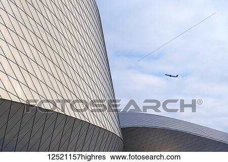 Stock Photograph - Plane taking off behind the Blue Planet Aquarium; Copenhagen, Denmark. Fotosearch