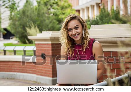 Portrait of a beautiful young female university student using her laptop outside on the campus; Edmonton, Alberta, Canada View Large Photo Image Stock Photograph - Portrait of a beautiful young female university student using her laptop outside on the campus; Edmonton, Alberta, Canada. Fotosearch