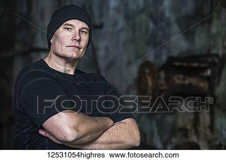 Stock Photograph - Portrait of a man standing with his arms crossed; Djupavik, West Fjords, Iceland. Fotosearch