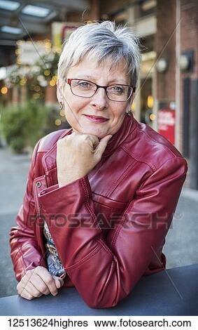 Portrait of a mature woman in a red leather jacket sitting at a table with her chin resting in her hand; Vancouver, British Columbia, Canada View Large Photo Image Stock Photograph - Portrait of a mature woman in a red leather jacket sitting at a table with her chin resting in her hand; Vancouver, British Columbia, Canada. Fotosearch