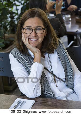 Portrait of a mature woman sitting at a table in a restaurant; Budapest, Budapest, Hungary View Large Photo Image Stock Photograph - Portrait of a mature woman sitting at a table in a restaurant; Budapest, Budapest, Hungary. Fotosearch