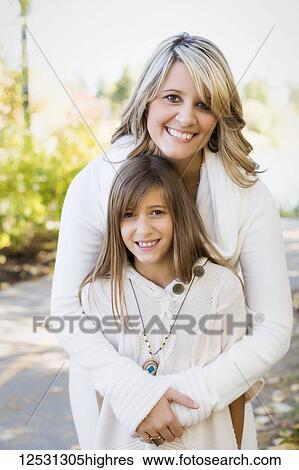 Portrait of a mother and daughter standing on a park trail in autumn with the mother's arms in an embrace around her daughter; Edmonton, Alberta, Canada View Large Photo Image Stock Photograph - Portrait of a mother and daughter standing on a park trail in autumn with the mother's arms in an embrace around her daughter; Edmonton, Alberta, Canada. Fotosearch